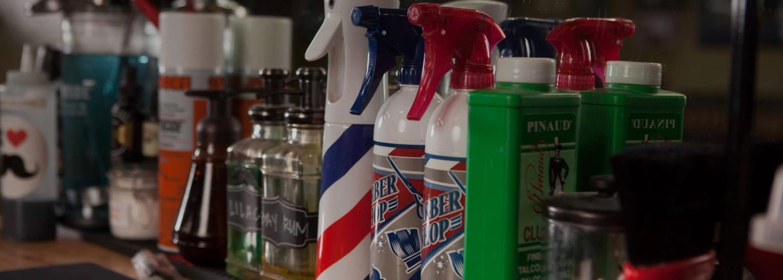 Row of barber spray bottles and grooming products on a station