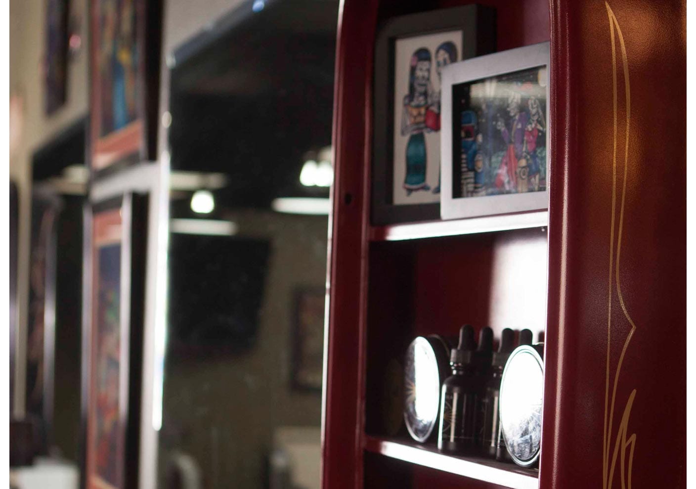 Close-up of a red station cabinet with framed artwork and grooming bottles