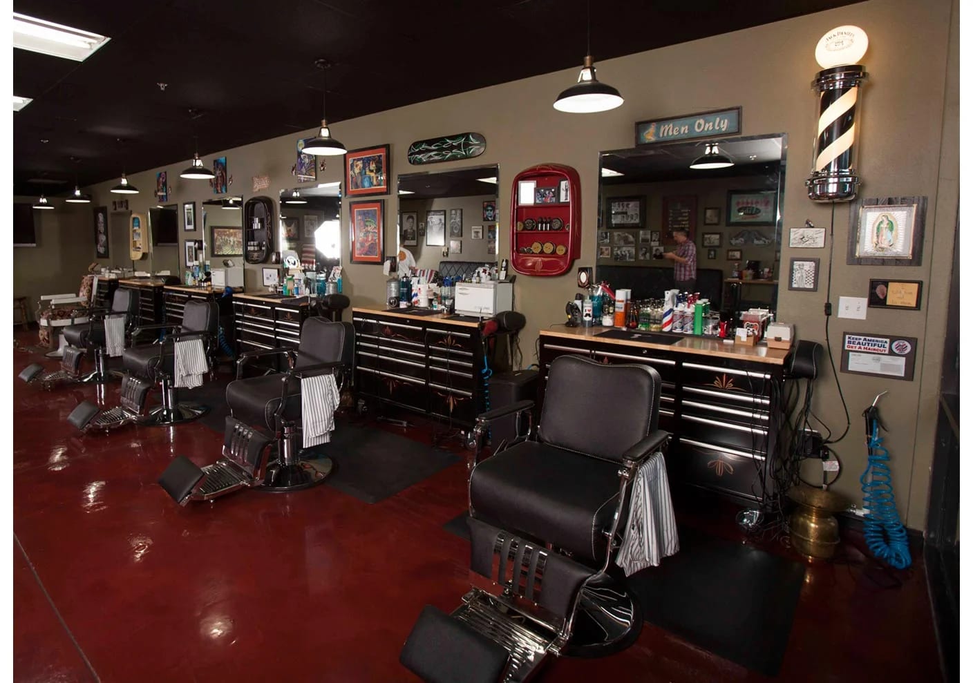 Wide view of the barber shop floor with vintage chairs, stations, and a barber pole